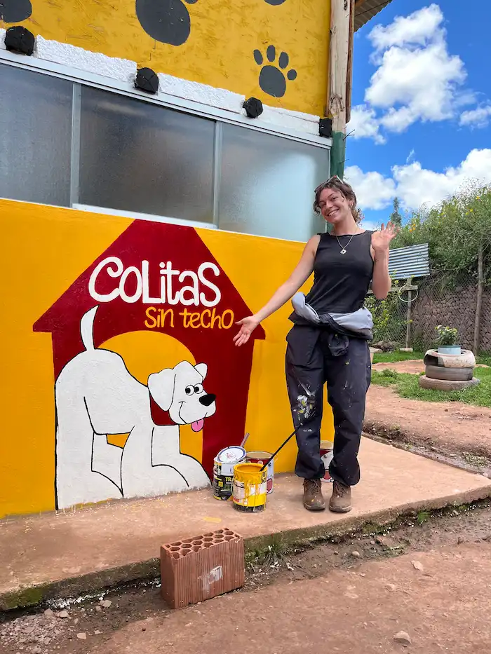 Voluntaria junto al mural que pinto